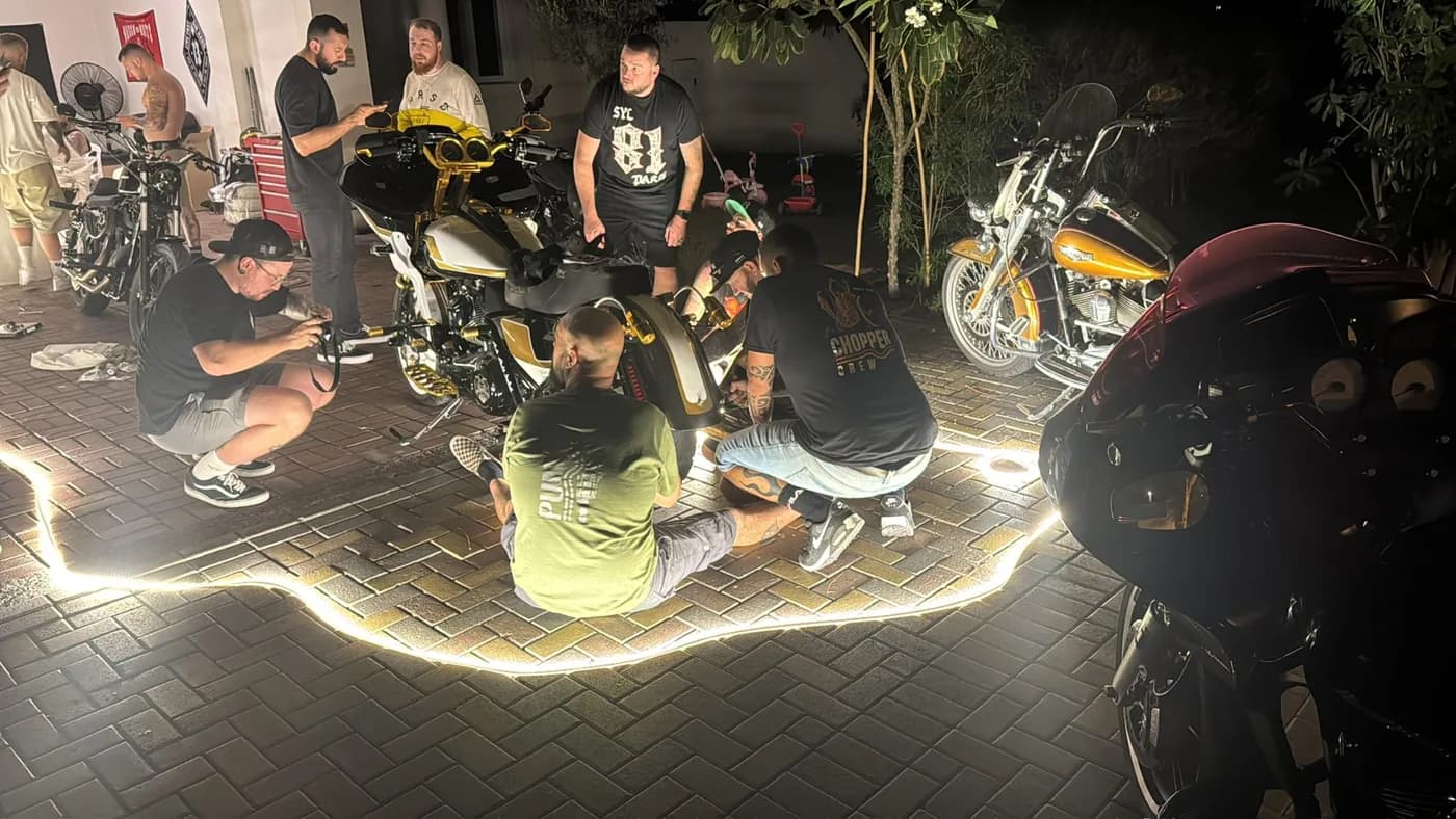 Clubstyle crew gathered around a gold-and-white custom bagger at a late-night driveway build session
